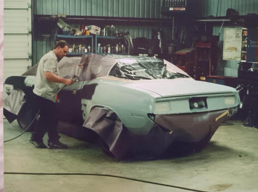 Dan Powell painting the 'Cuda old school — no mask, spray gun in hand, working the rear quarter panel in his Collinsville Oklahoma shop
