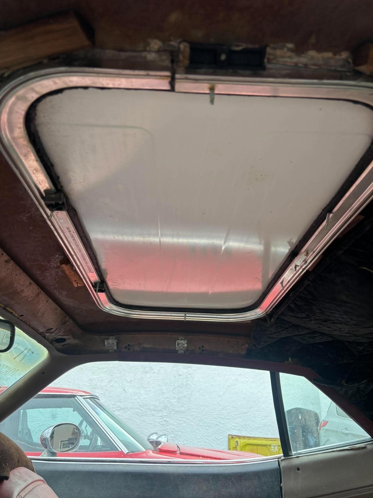 Interior cabin view looking up through the sunroof opening — raw fabrication and frame visible
