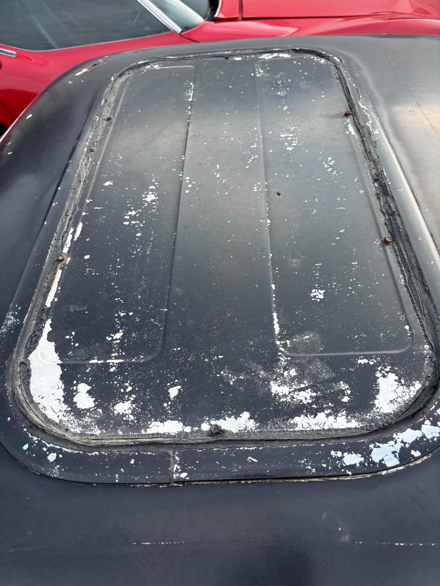 Top-down view of the raw sunroof cut on a 71 Cuda roof — weathered seal and fabricated panel
